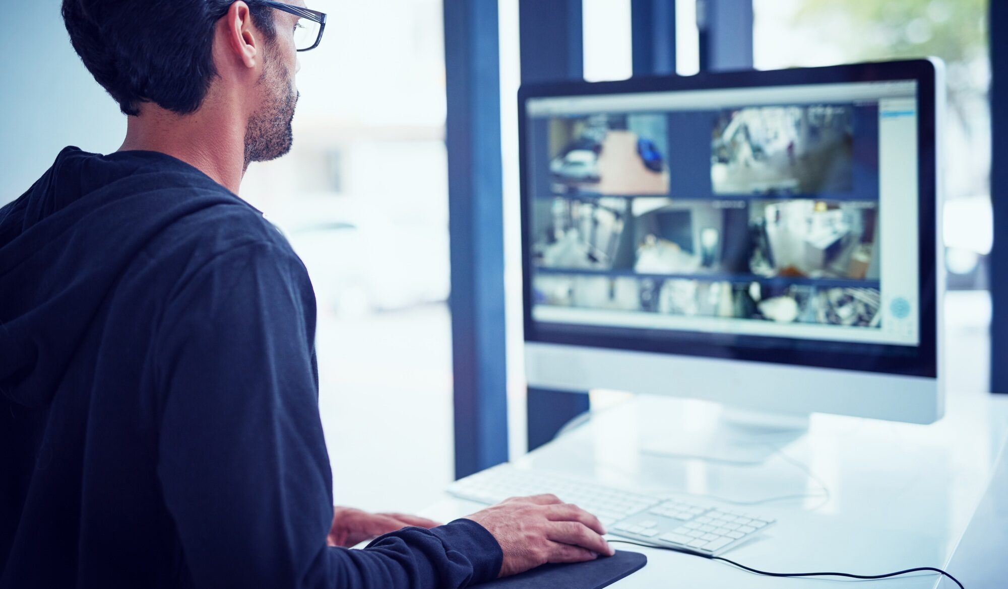 Cropped shot of a young man watching security footage on his computer